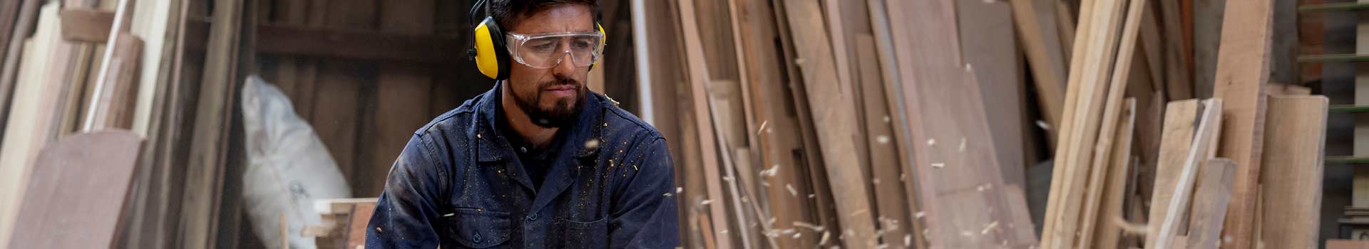 Person working with wood wearing safety glasses and ear muffs.
