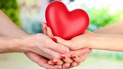 Man and woman's hands cradling a red heart