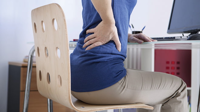 Hand holding lower back sitting on chair