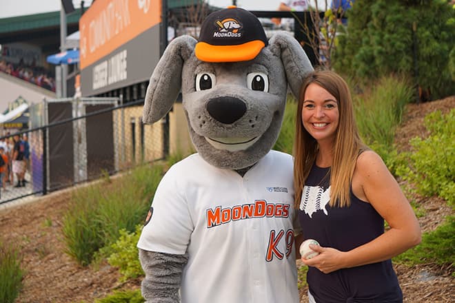 Samantha Kaul standing with Muttnik, Moondogs mascot
