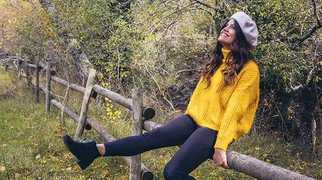 Happy woman sitting on log fence