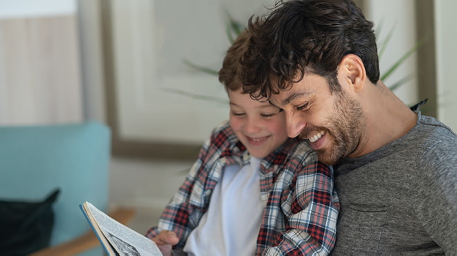 Child on adult's lap, both reading