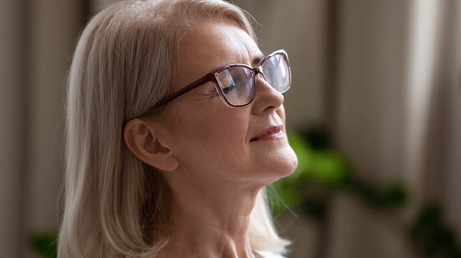 Woman wearing glasses, eyes closed and smiling