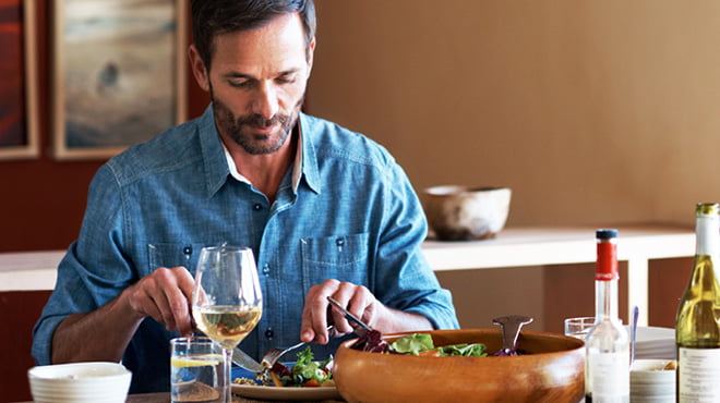 Forking salad, glass of wine on table