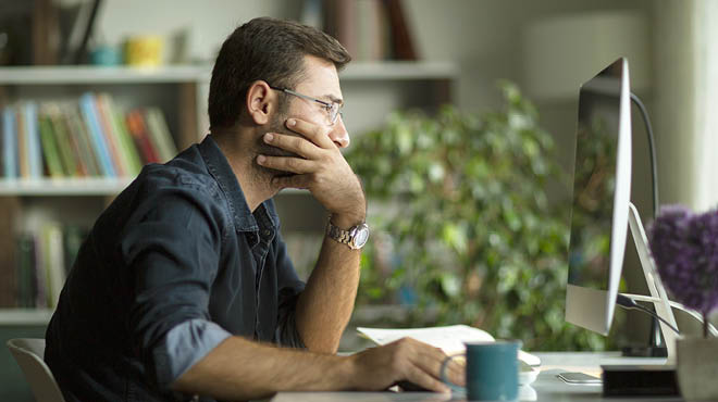 Hand on face looking at computer screen