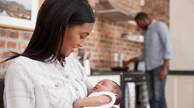 Mom holding baby as dad cooks