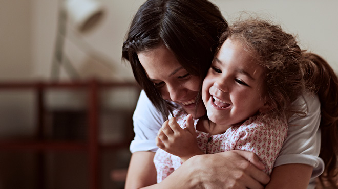 Parent hugging child from behind