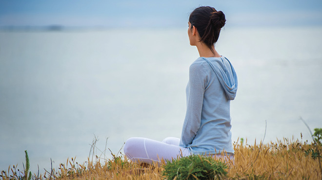 Sitting cross-legged on field near water