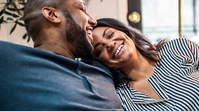 Couple with head resting on shoulder and laughing