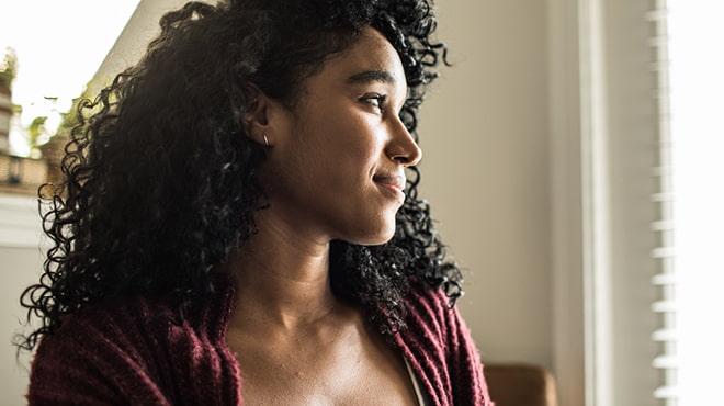 Person with dark, curly hair facing sunny window