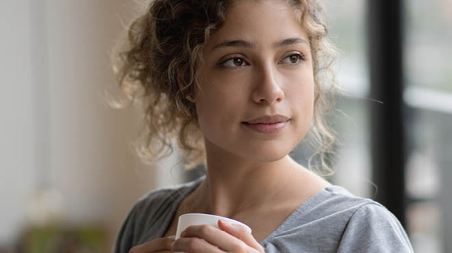 Young person holding coffee cup to upper chest