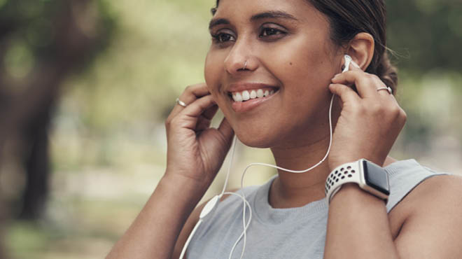 Holding earbuds in ears, wearing fitness watch