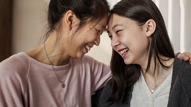 Parent and child laughing and touching foreheads