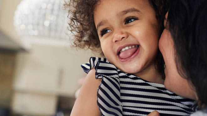 Parent snuggling smiling toddler