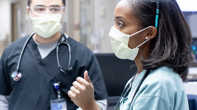 Two masked medical professionals