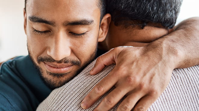 Two people hugging, resting head on shoulder, arm around neck