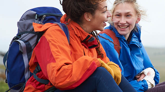 Two young adults wearing coats and backpacks