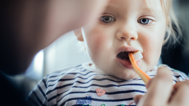 Adult brushing toddler's teeth