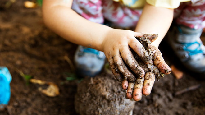 Child hands making mud pie