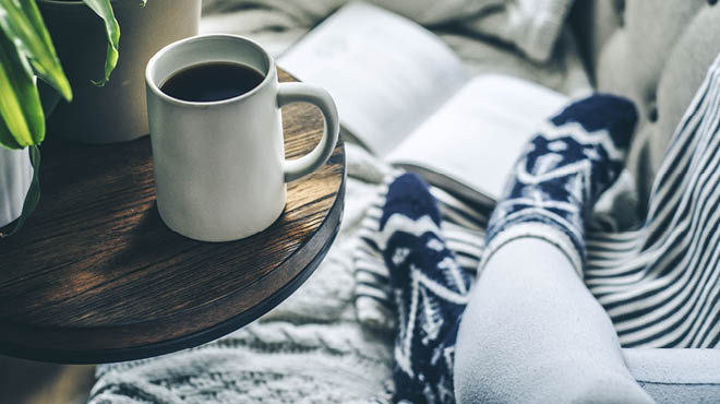 Sitting on sofa with cozy socks and a cup of coffee on table