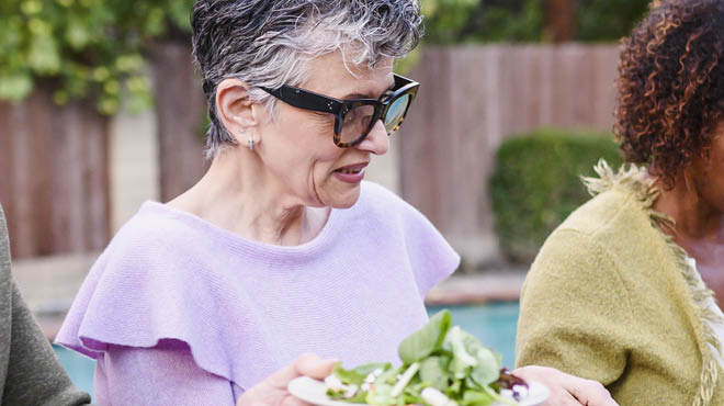 Person dishing salad, dining outdoors