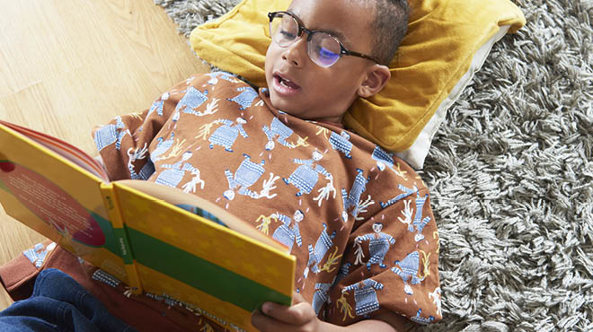 Child lying on floor reading