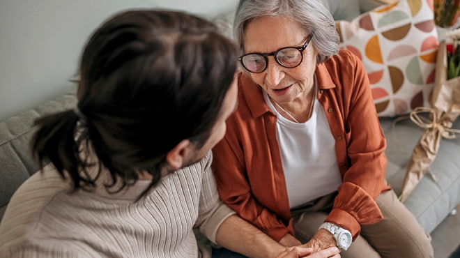 Elderly person sitting on sofa with younger person