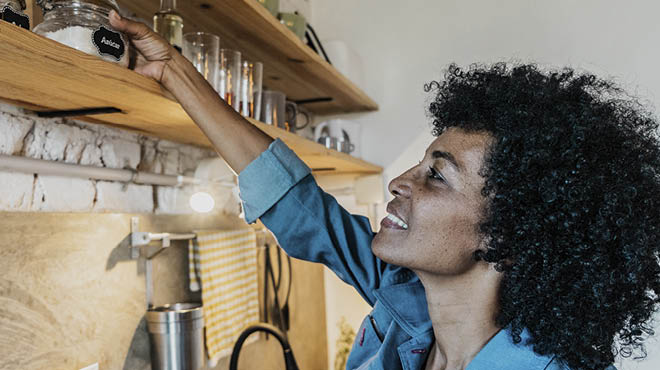 Lady reaching for upper kitchen shelf